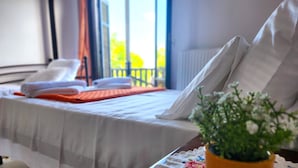 Habitación de hotel con cama, vistas al exterior y una planta en la mesita de noche.