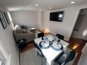 Cozy living space with a dining area, featuring a flat-screen TV, dining table, and comfortable seating.