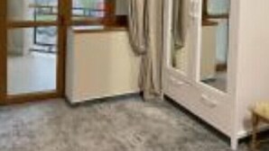 Una habitació amb una gran porta corredissa de vidre que dona a un balcó, un armari blanc i un sòl amb moqueta.