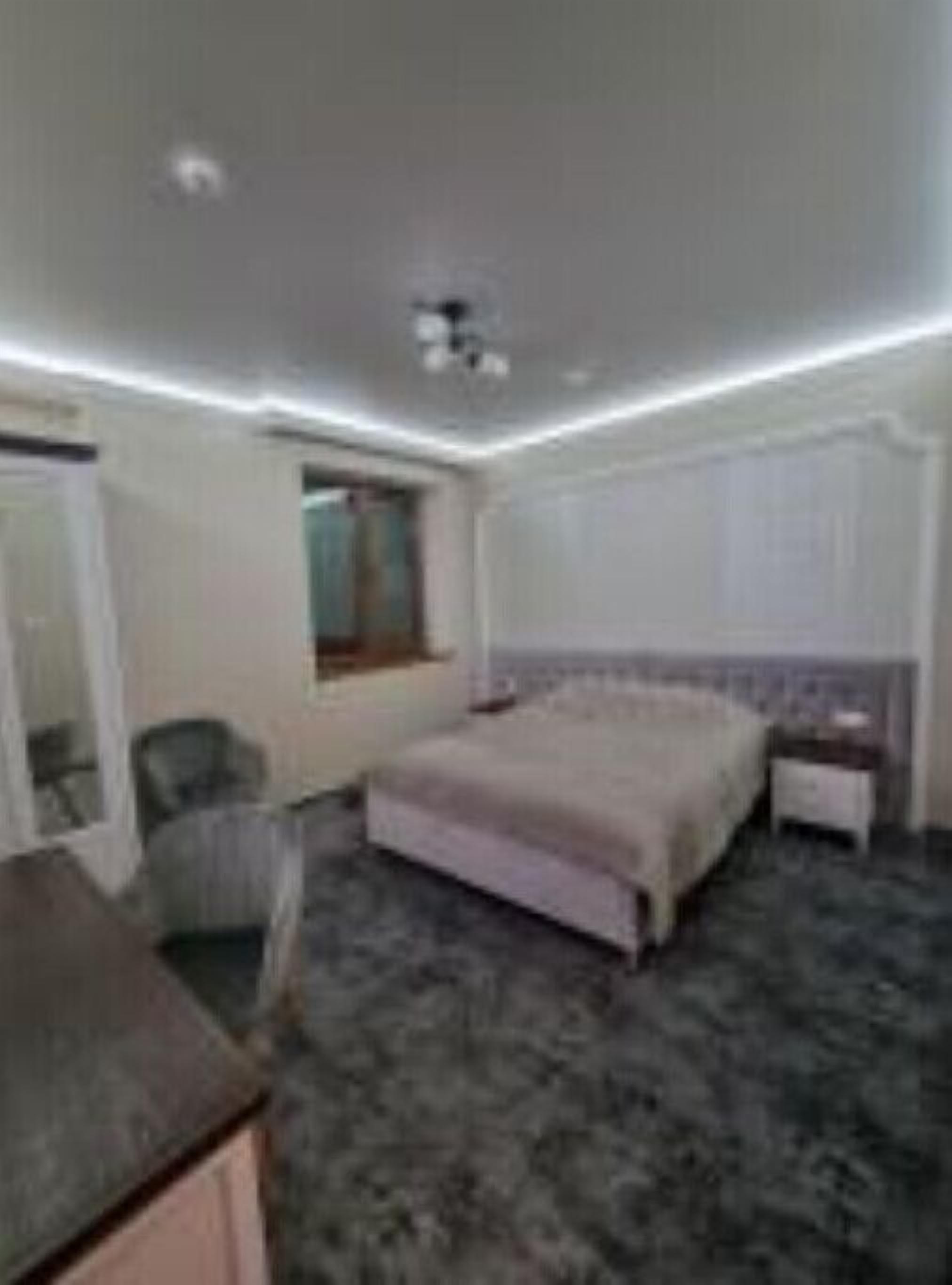 A hotel room with a bed, a chair, a desk, and a window.