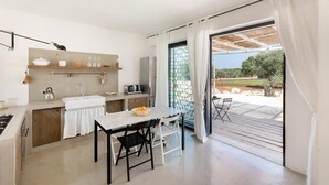 A modern kitchen with a dining area, a large sliding glass door leading to an outdoor patio. - Trullo Delle Stelle by Wonderful Italy (Ostuni)