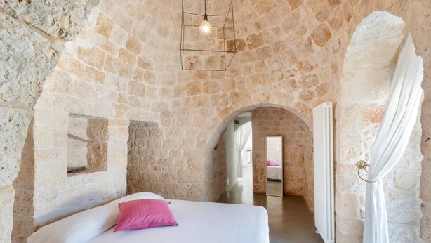 A stone-walled bedroom with a bed, a mirror, and a hanging light fixture. - Trullo Delle Stelle by Wonderful Italy (Ostuni)