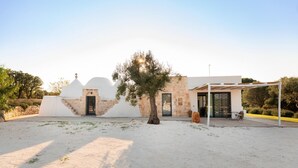 A modern building with a stone facade, a covered patio area, and a tree in the foreground. - Trullo Delle Stelle by Wonderful Italy (Ostuni)