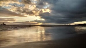 Een strand met een rustige zee en een bewolkte lucht.