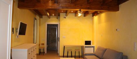 Un salon avec un plafond en bois, un canapé, une petite table et un meuble.