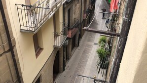A narrow street with buildings on either side, featuring balconies with metal railings and a pedestrian walkway. - CASA PEQUE (Laguardia)