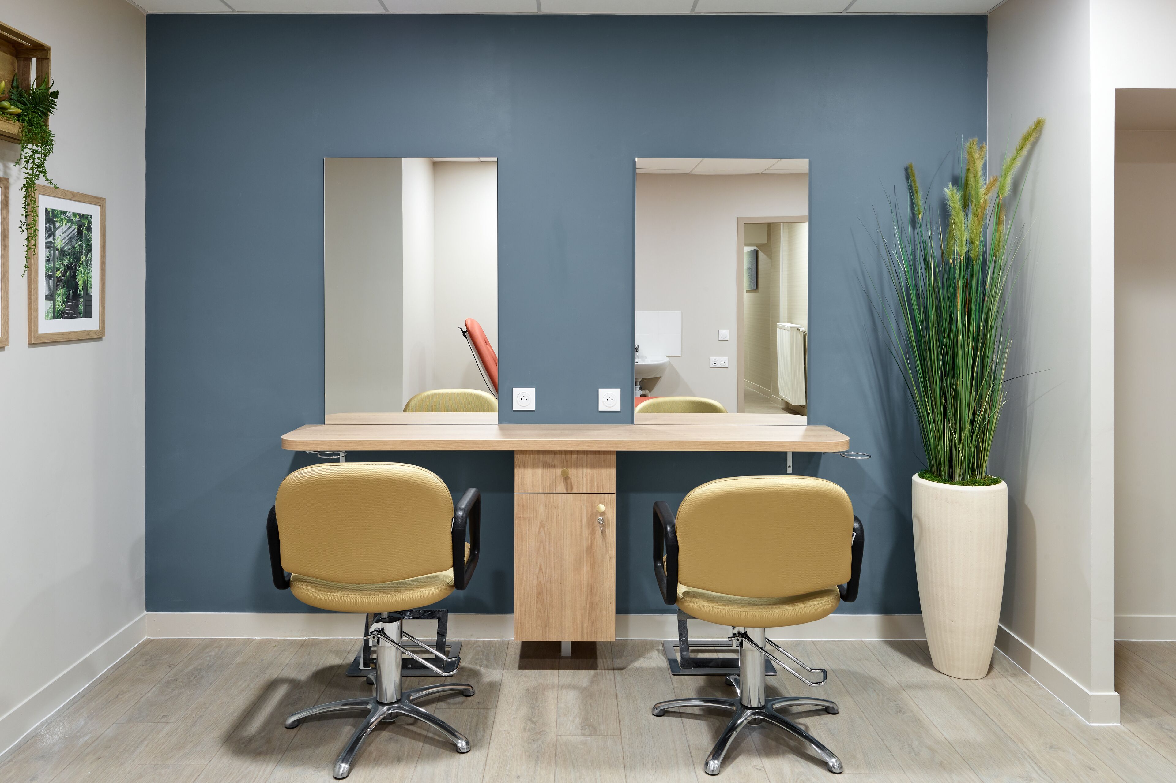 A conference room with a long table, two yellow chairs, a large mirror, and a tall potted plant.
