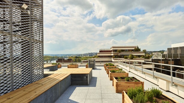 Terraza en la azotea con jardineras de madera y valla metálica.