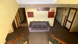 A staircase with a grey sofa at the bottom, wooden handrails, and a wall with a window and a sign. - El Puma (Cusco)