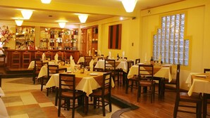 A restaurant with multiple tables and chairs, a bar area, and large windows. - El Puma (Cusco)