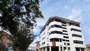 A multi-story building with a modern design, featuring a corner entrance and large windows. - El Puma (Cusco)