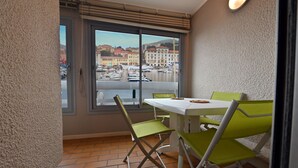 Ein Balkon mit Tisch und Stühlen, Blick auf eine Marina mit Booten und eine Stadtlandschaft im Hintergrund.