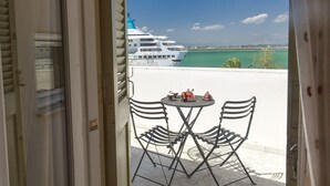 A balcony with two chairs and a small table, overlooking a cruise ship and a calm sea. - Family Latini Hotel (Nafplio)