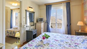 A hotel room with a bed, a desk, a television, and a window with curtains. - Family Latini Hotel (Nafplio)