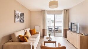 A modern living room with a sofa, coffee table, and television. - Zenao Appart'hôtels Montreuil (Montreuil)