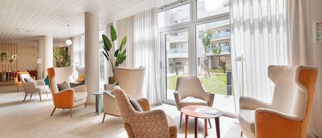 Un vestíbulo moderno de hotel con un diseño espacioso, ventanas amplias y diversas opciones de asientos.