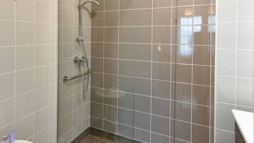 Un baño con cabina de ducha de vidrio, inodoro y lavabo.