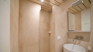 Een badkamer met een houten plafond, een witte wastafel en een spiegel erboven.