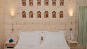 Een houten kamer met een bed, twee nachtkastjes en meerdere wandlampen.
