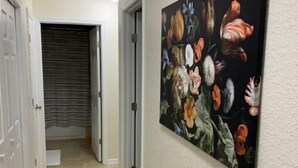 Een gang met een betegelde vloer, witte wanden en een deur naar een kamer.