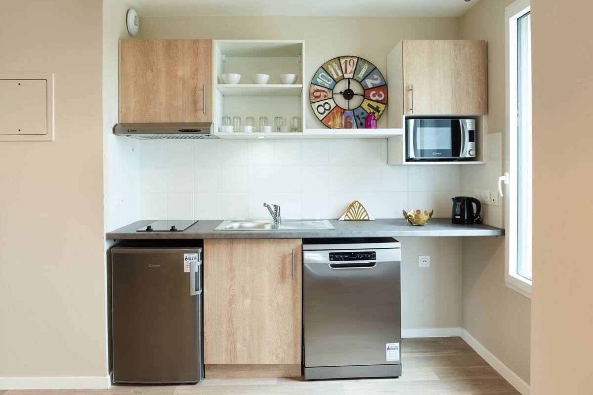 Uma cozinha compacta com máquina de lavar louça, micro-ondas e armários de madeira.