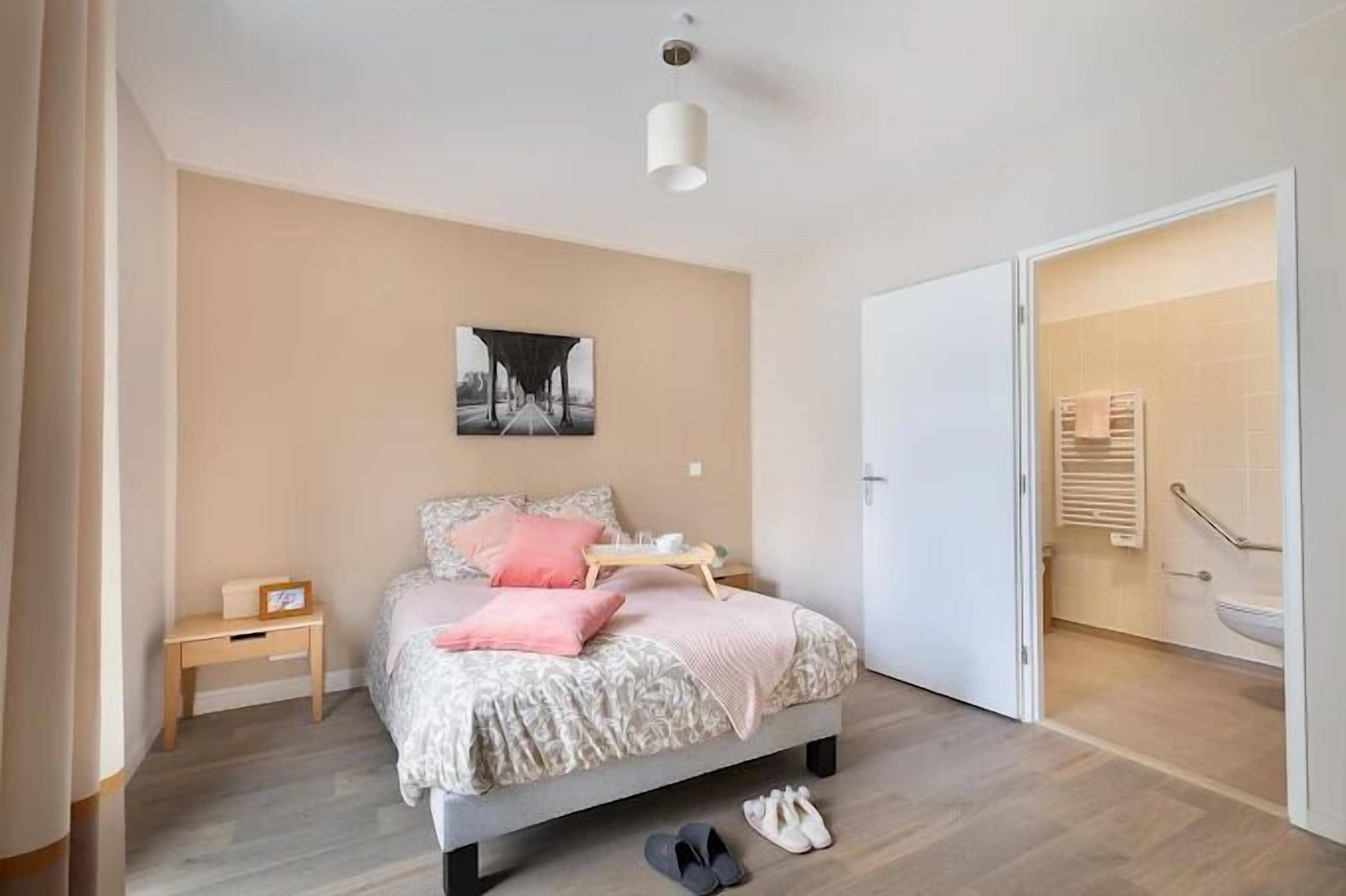 A bedroom with a bed, bedside table, and a door leading to a bathroom.