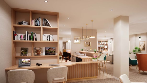 A modern interior with a wooden reception desk, bookshelves, and a dining area with chairs and tables. - Zenao Appart’hôtels Le Raincy (Le Raincy)