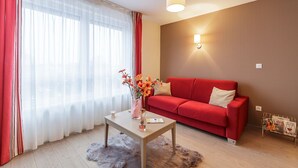 Una sala de estar moderna con un sofá rojo, una mesa de centro de madera y un jarrón con flores.