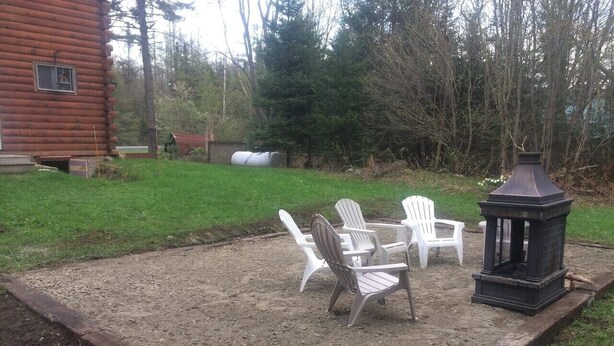 Patiolla on Adirondack-tyylisiä puutarhatuoleja, lyhty ja puinen terassi.