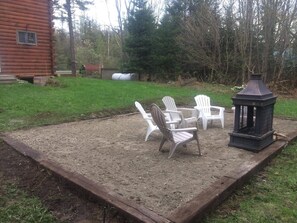 Eine Terrassenfläche mit Adirondack-Stühlen, einer Laterne und einem Holzdeck.