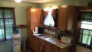 Kompakti keittiö, jossa on puiset kaapit, pesuallas, vesihana ja liesi.