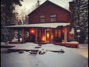 Cozy cabin with a traditional design, featuring a porch with seating and a fireplace.