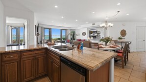 A modern kitchen with granite countertops, a dishwasher, and a dining area with a table and chairs.