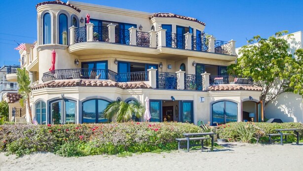 A multi-story building with balconies, large windows, and a landscaped garden.