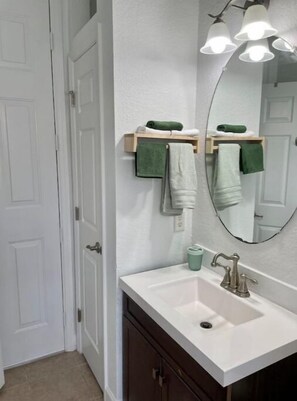 A bathroom with a white sink, a mirror, and a towel rack with multiple towels. - Cheerful 4 Bed, 3 Bath Home with Screened Pool (Winter Haven)