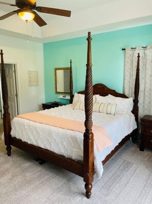 A four-poster bed with a wooden frame and a white bedspread. - Cheerful 4 Bed, 3 Bath Home with Screened Pool (Winter Haven)