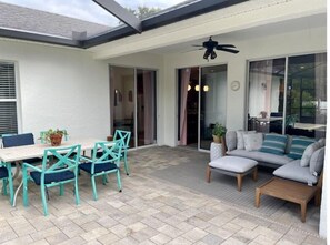 A patio with a table and chairs, a sofa, and a ceiling fan. - Cheerful 4 Bed, 3 Bath Home with Screened Pool (Winter Haven)