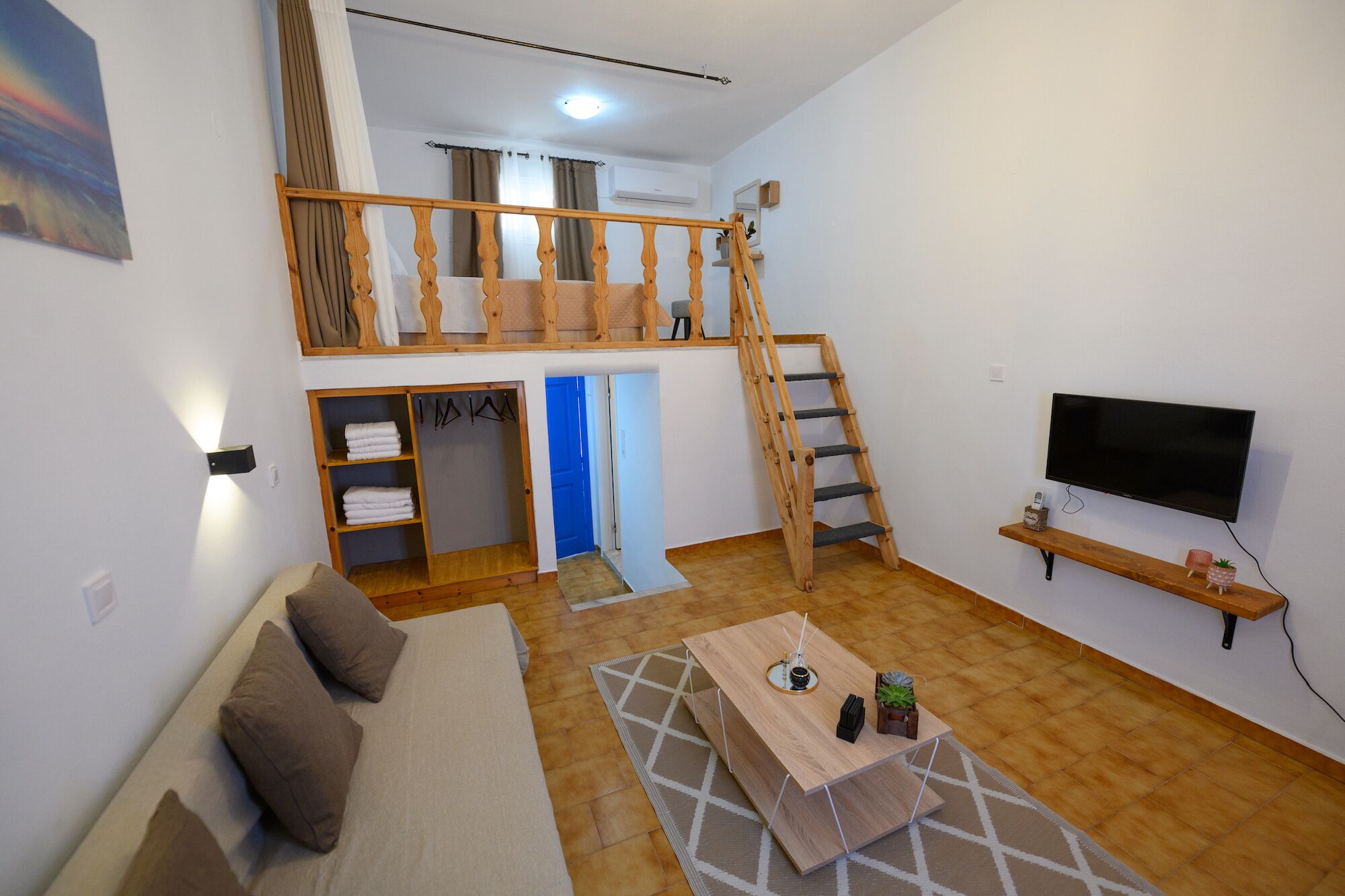 Un appartement moderne avec une chambre en mezzanine, un téléviseur et une table basse en bois.