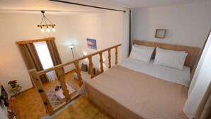 Een slaapkamer met een houten bed, een hoofdbord, een nachtkastje, een lamp en uitzicht op een balkon.