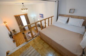 Ein Schlafzimmer mit einem großen Bett, einem Holzkopfstück und Blick auf einen Balkon.