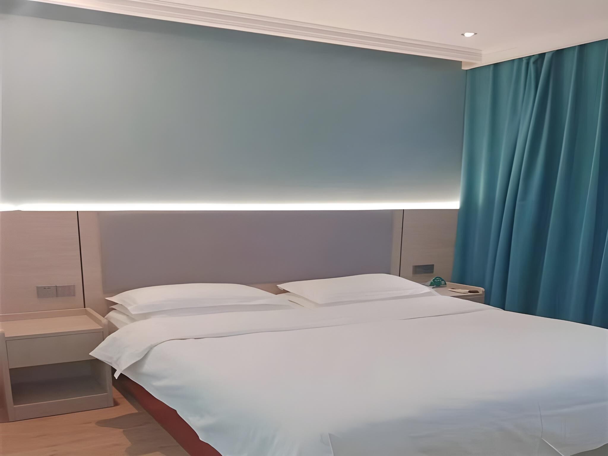 A hotel room with a bed, nightstands, and a wall-mounted light fixture.