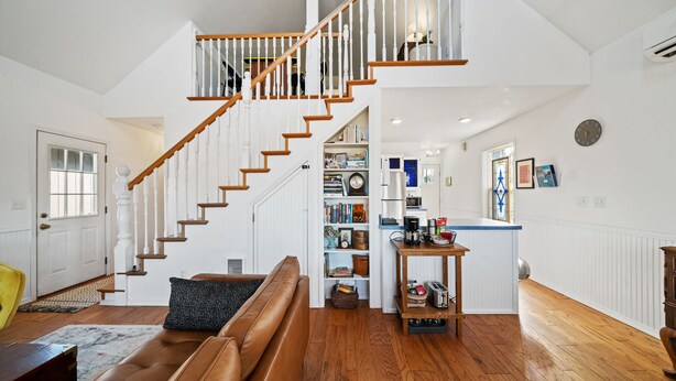 A spacious living area with a wooden staircase, a kitchen with white cabinets, and a dining area with a table and chairs. - Relax and unwind in a tranquil space one block from the beach (Manzanita)