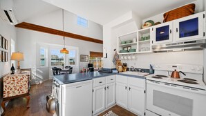 A modern kitchen with white cabinets, a built-in stove, and a dining area with a table and chairs. - Relax and unwind in a tranquil space one block from the beach (Manzanita)