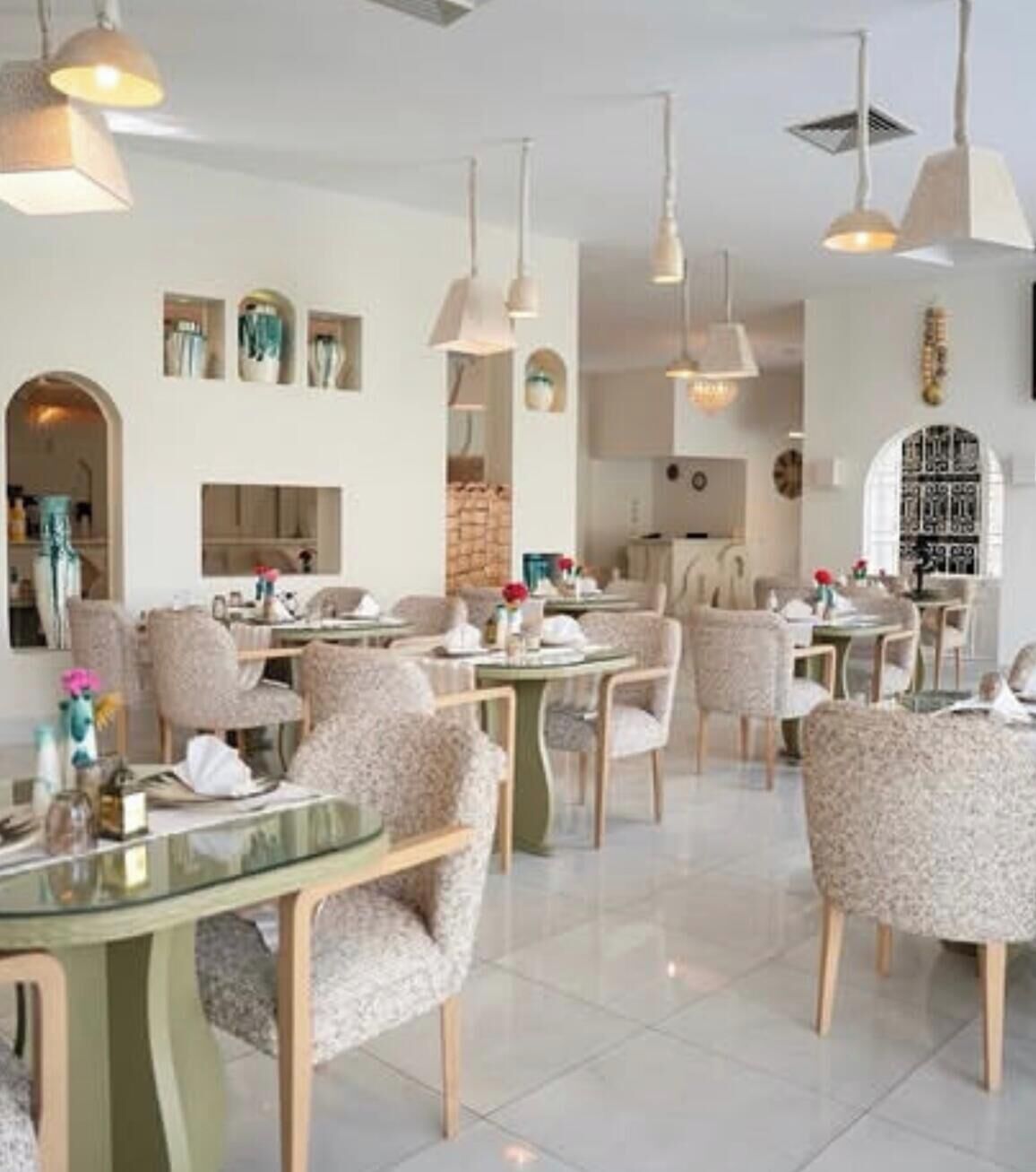 Comedor con mesas y sillas redondas, iluminación colgante y un diseño moderno y minimalista.