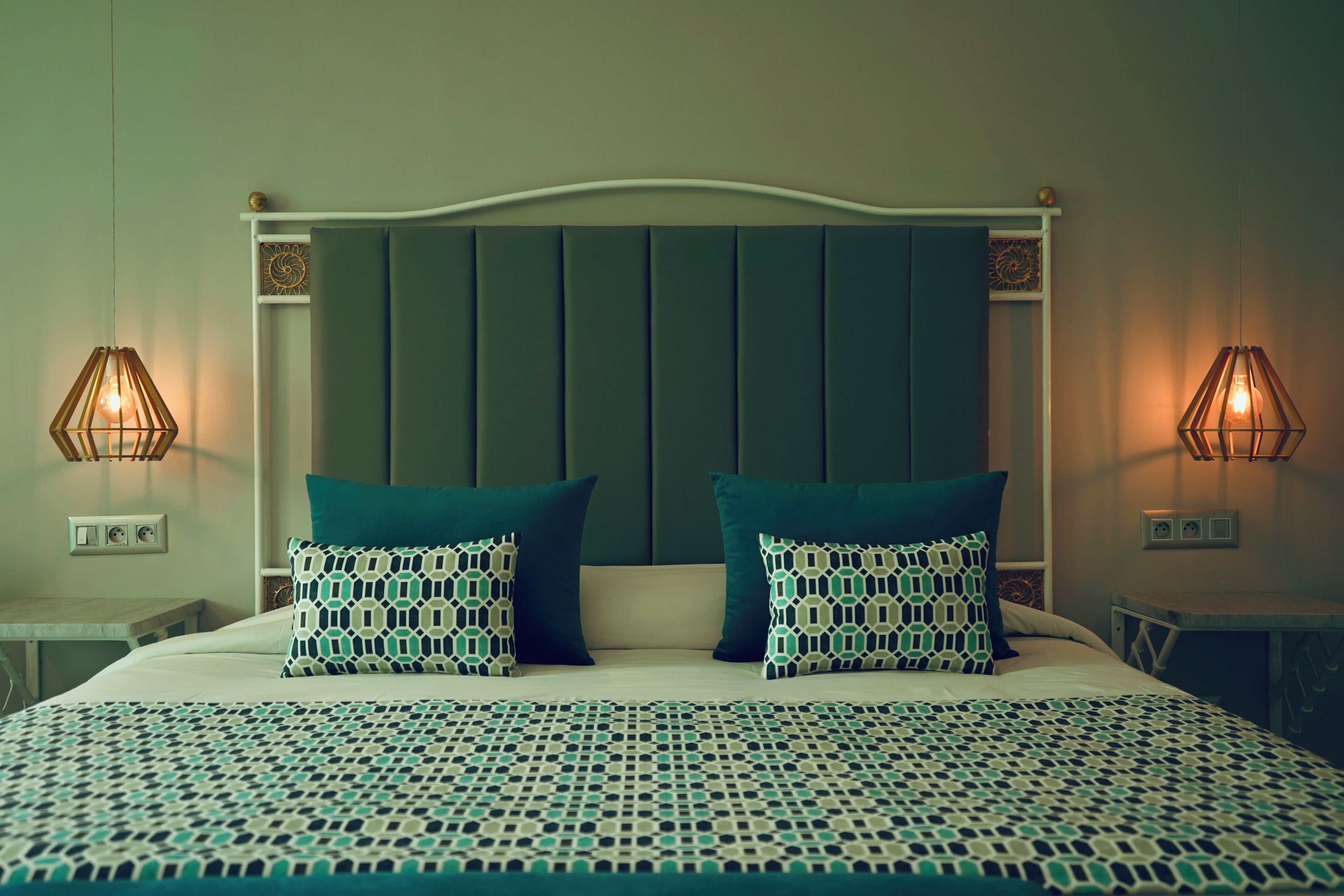 A neatly made bed with patterned pillows and a matching bedspread, flanked by two bedside tables with lamps.