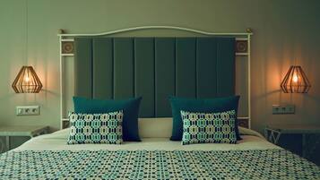 A neatly made bed with patterned pillows and a matching bedspread, flanked by two bedside tables with lamps.