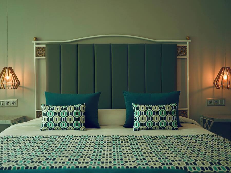 A neatly made bed with patterned pillows and a matching bedspread, flanked by two bedside tables with lamps.