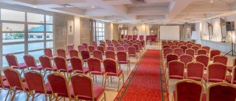 A conference room with rows of red chairs, a red carpet, and large windows.