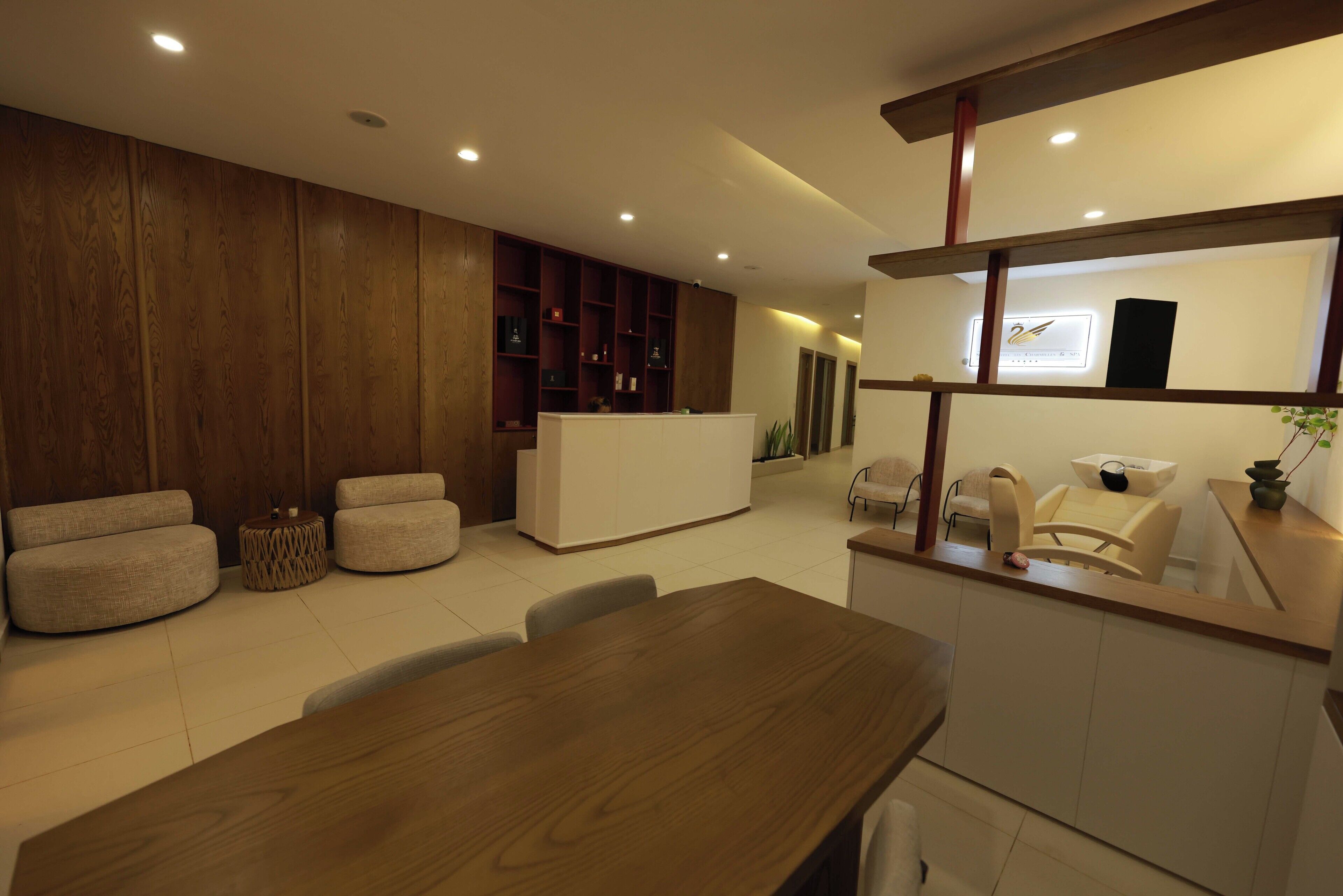 A modern interior with a wooden reception desk, cushioned seating, and a dining area.