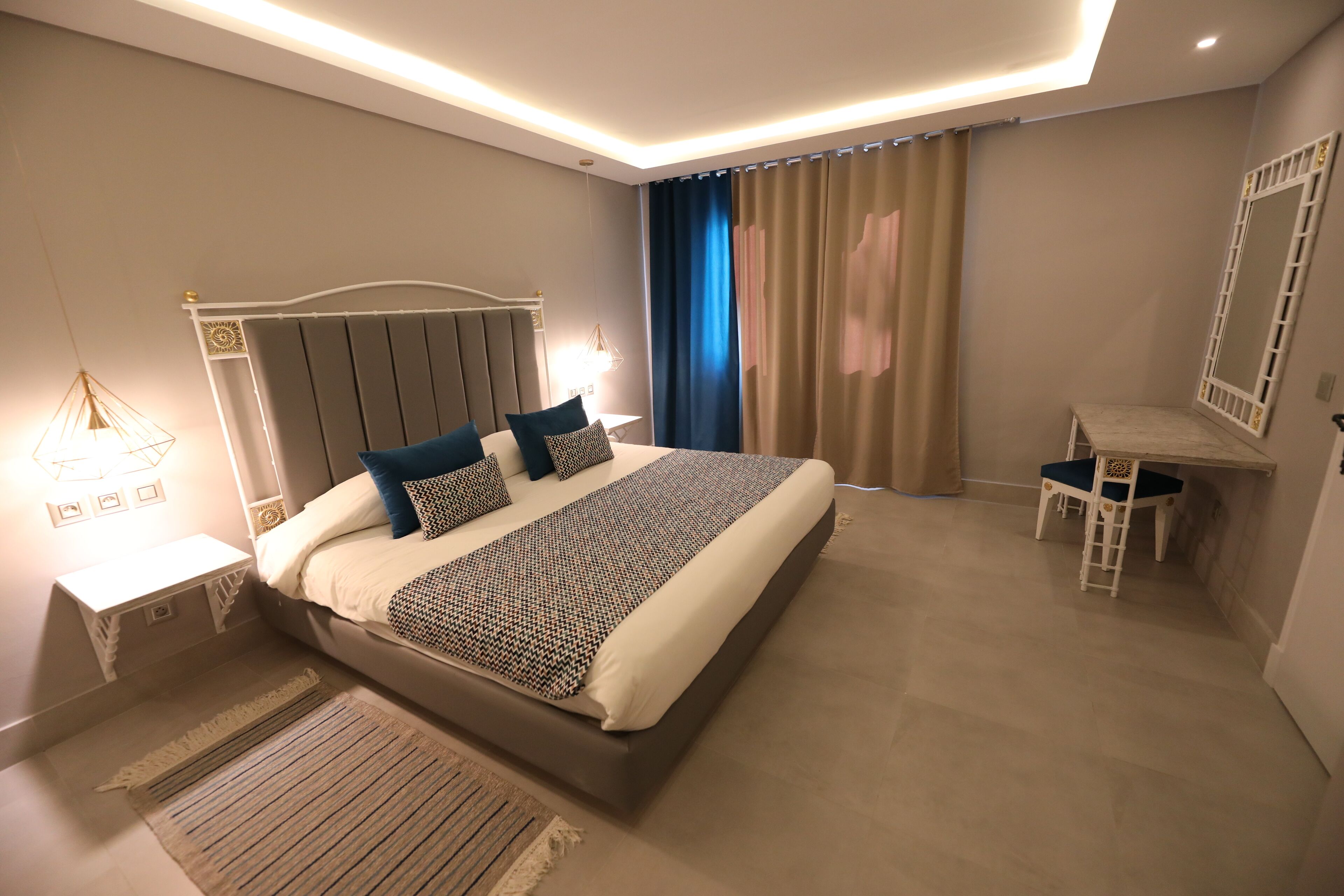 Une chambre moderne avec un grand lit, des tables de chevet, un bureau et un miroir.